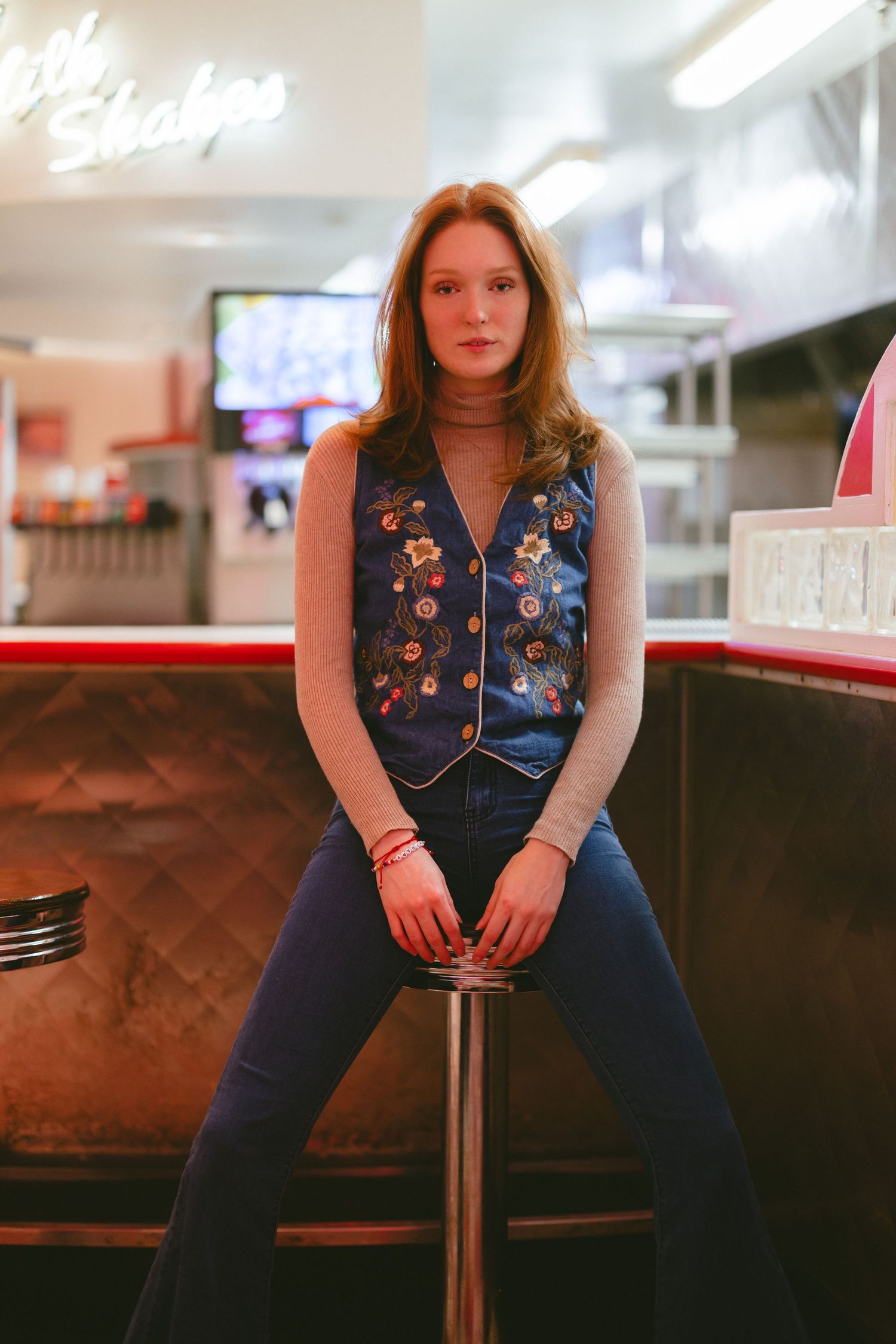 Casual diner photoshoot featuring denim vest and vintage-inspired styling.