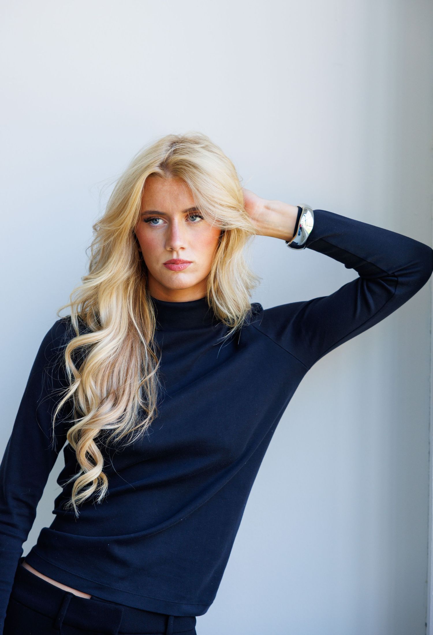 Fashion model in navy sweater poses against white background in series of artistic portrait shots.