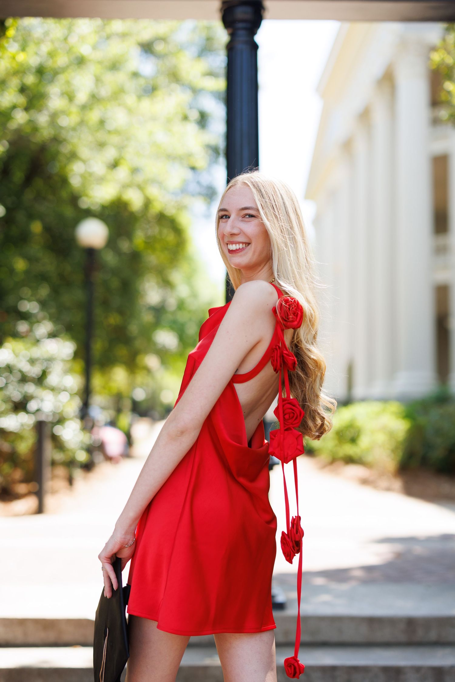 Red dress fashion photos taken outdoors with white columns and greenery.