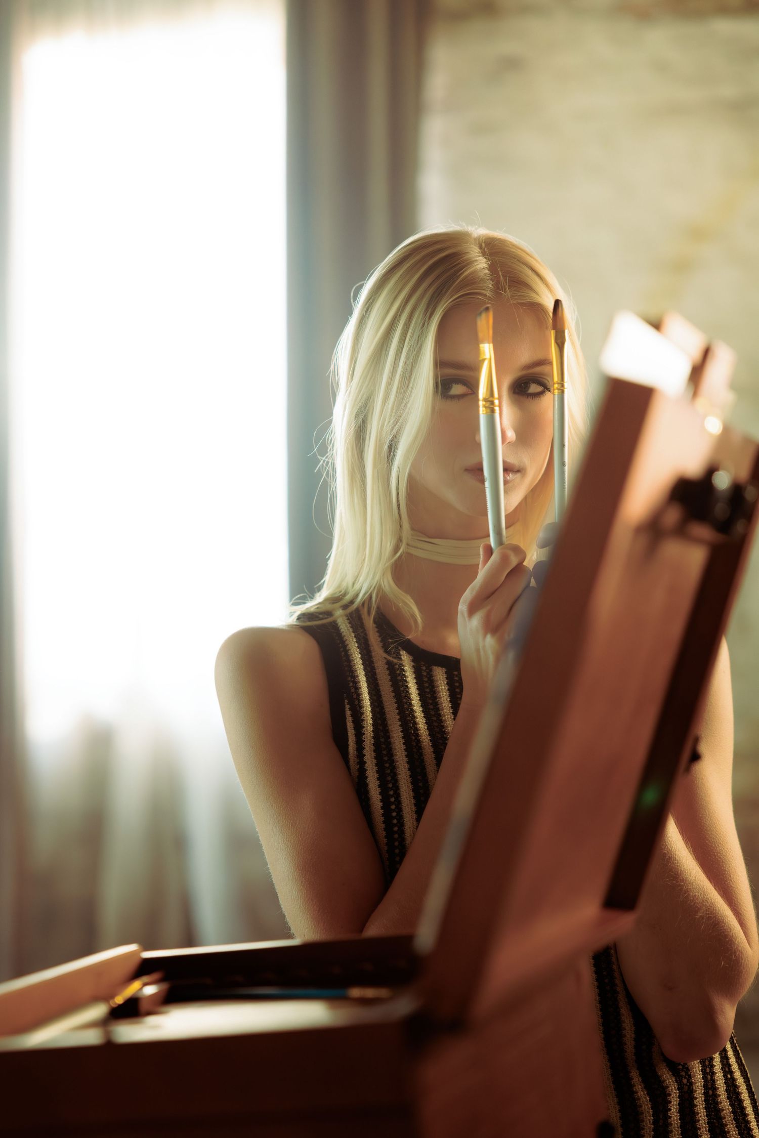 Artistic portrait with soft lighting shows woman peeking behind a book.