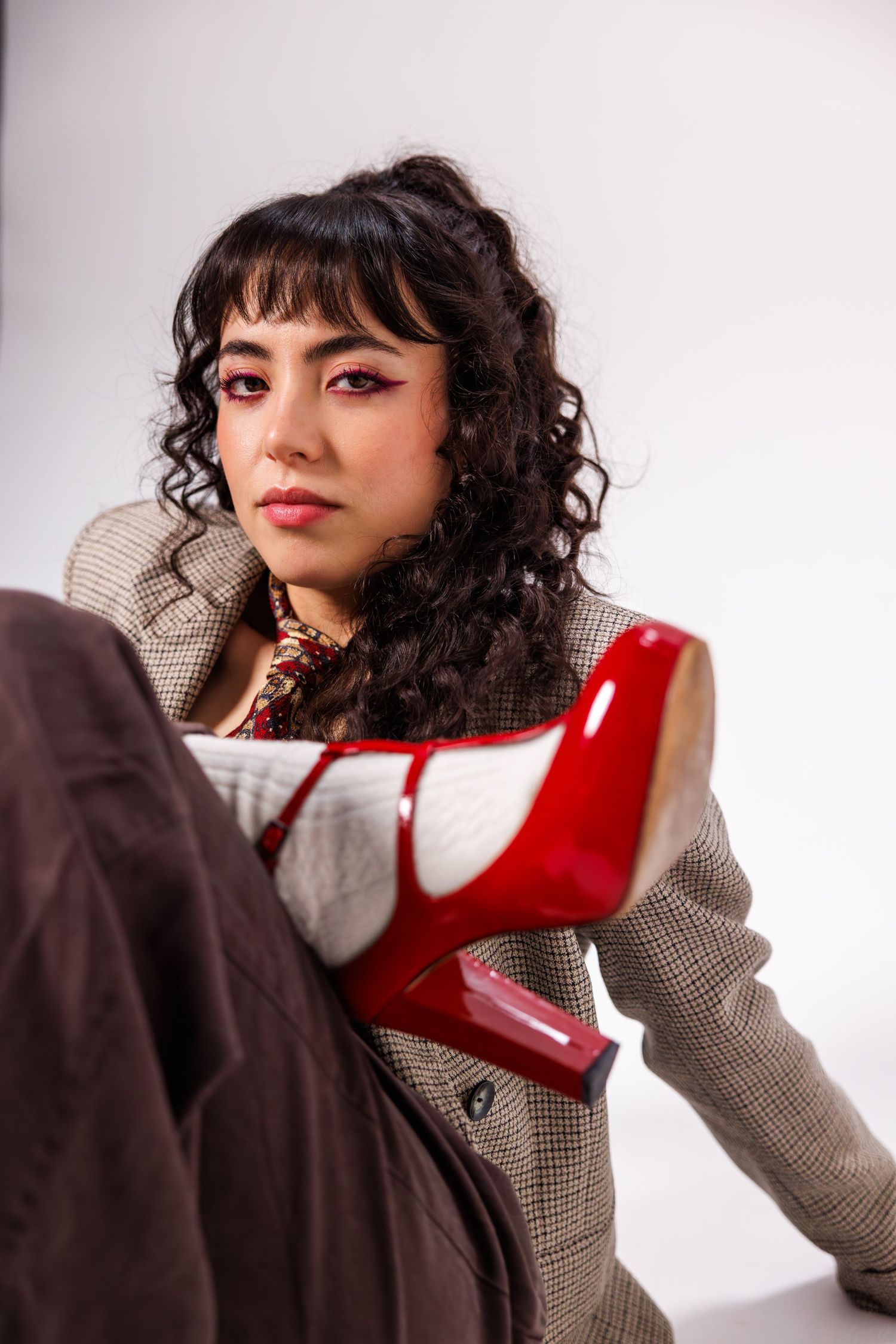 Fashion photos showcasing red heels and gray blazer in artistic poses on white backdrop.