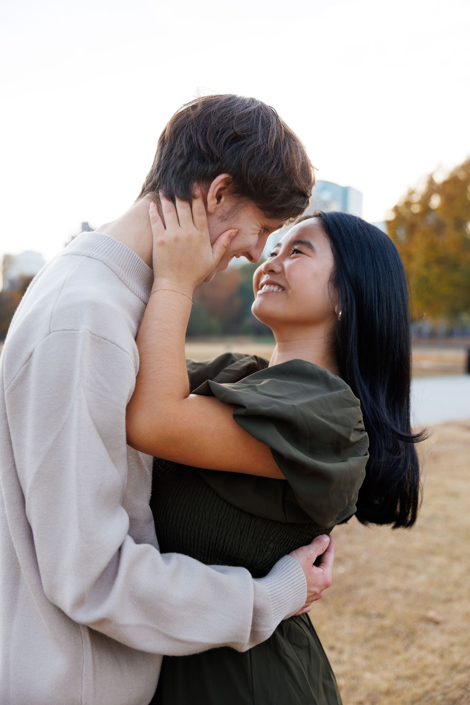 Romantic couple embracing and laughing together in a field during golden hour.