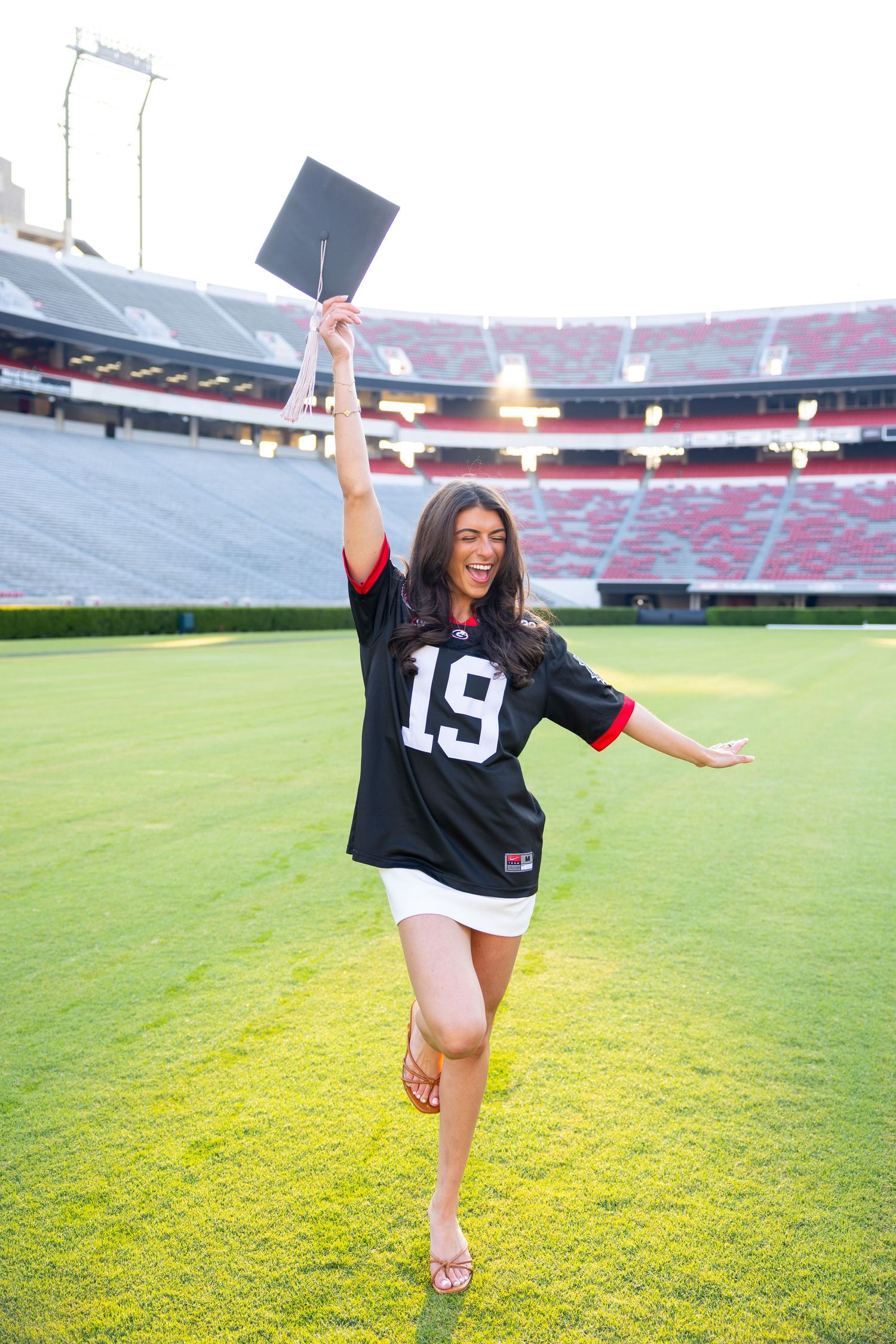 A dancer performs graceful poses on a green football field inside a large stadium.