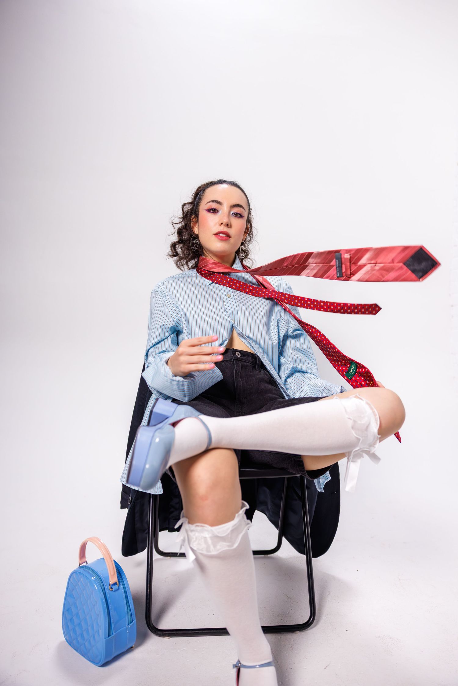 Modern fashion shoot featuring blue shirt, red tie and casual styling against white backdrop.