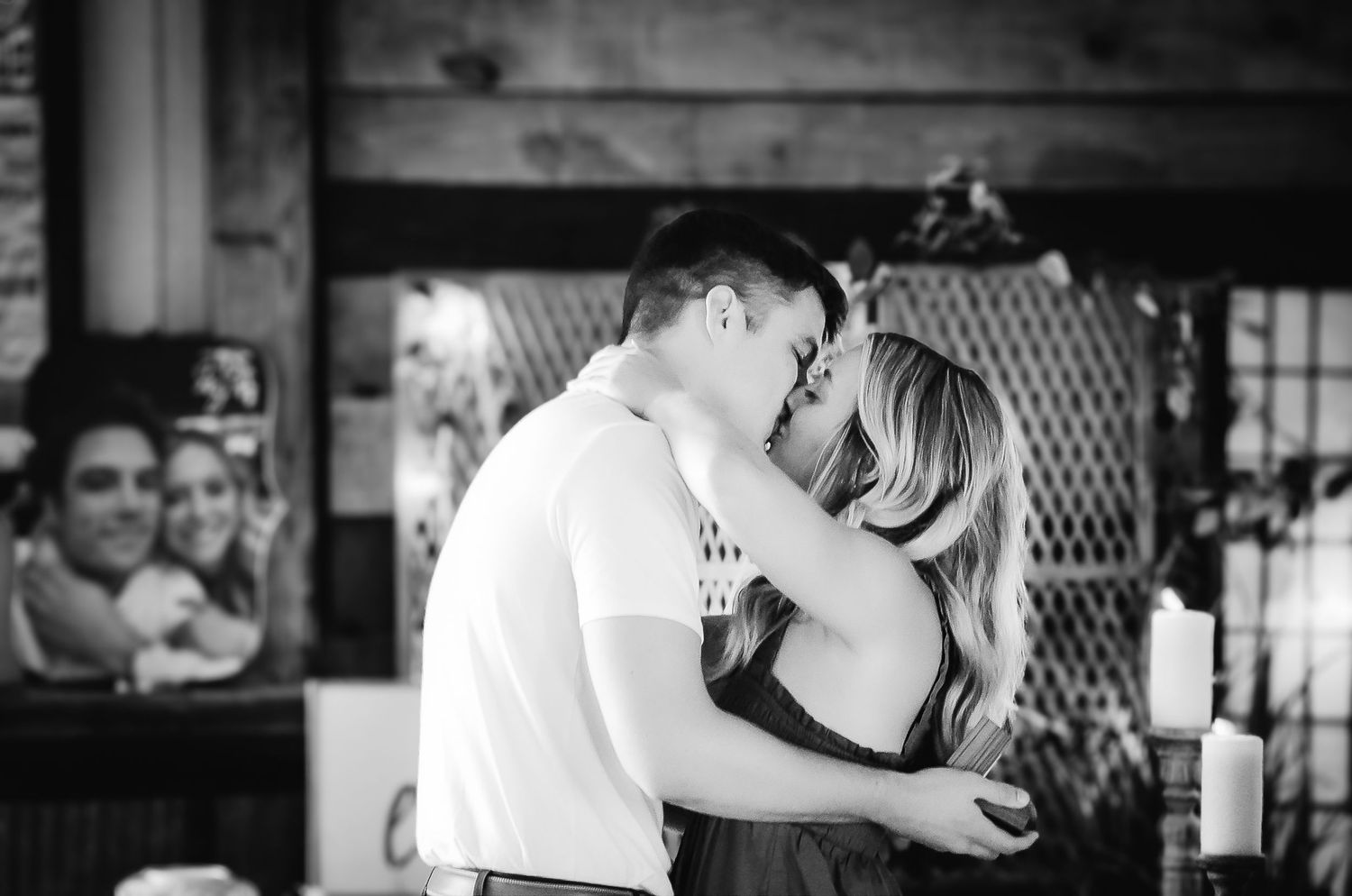 Black and white photo of couple sharing romantic moment in rustic setting.