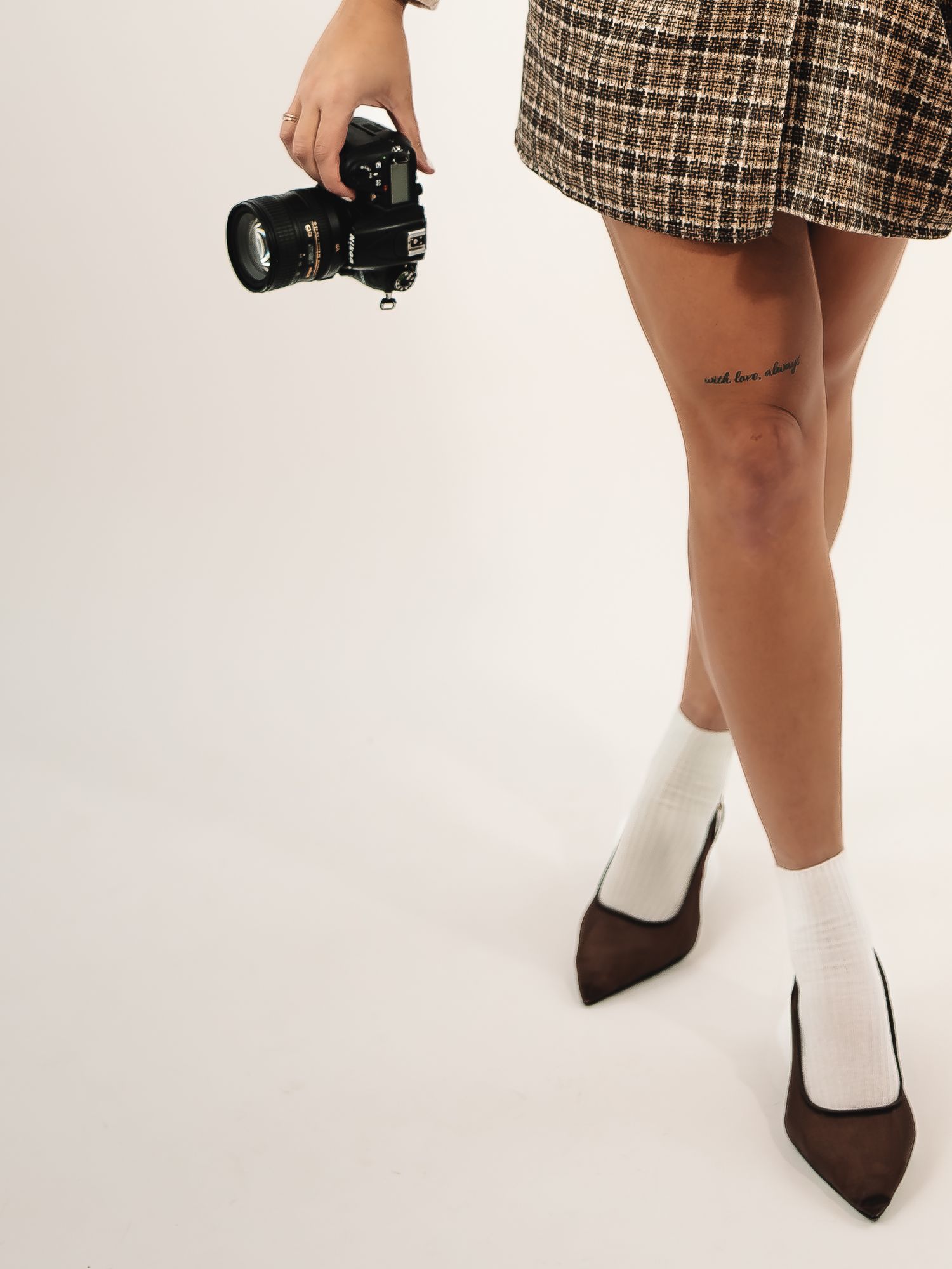 Close-up of feet wearing brown heels and white socks with camera in frame.