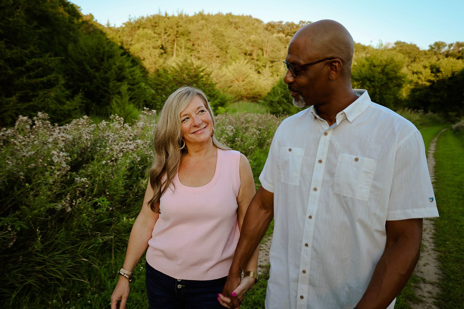 Couple walking together on nature trail during golden hour.