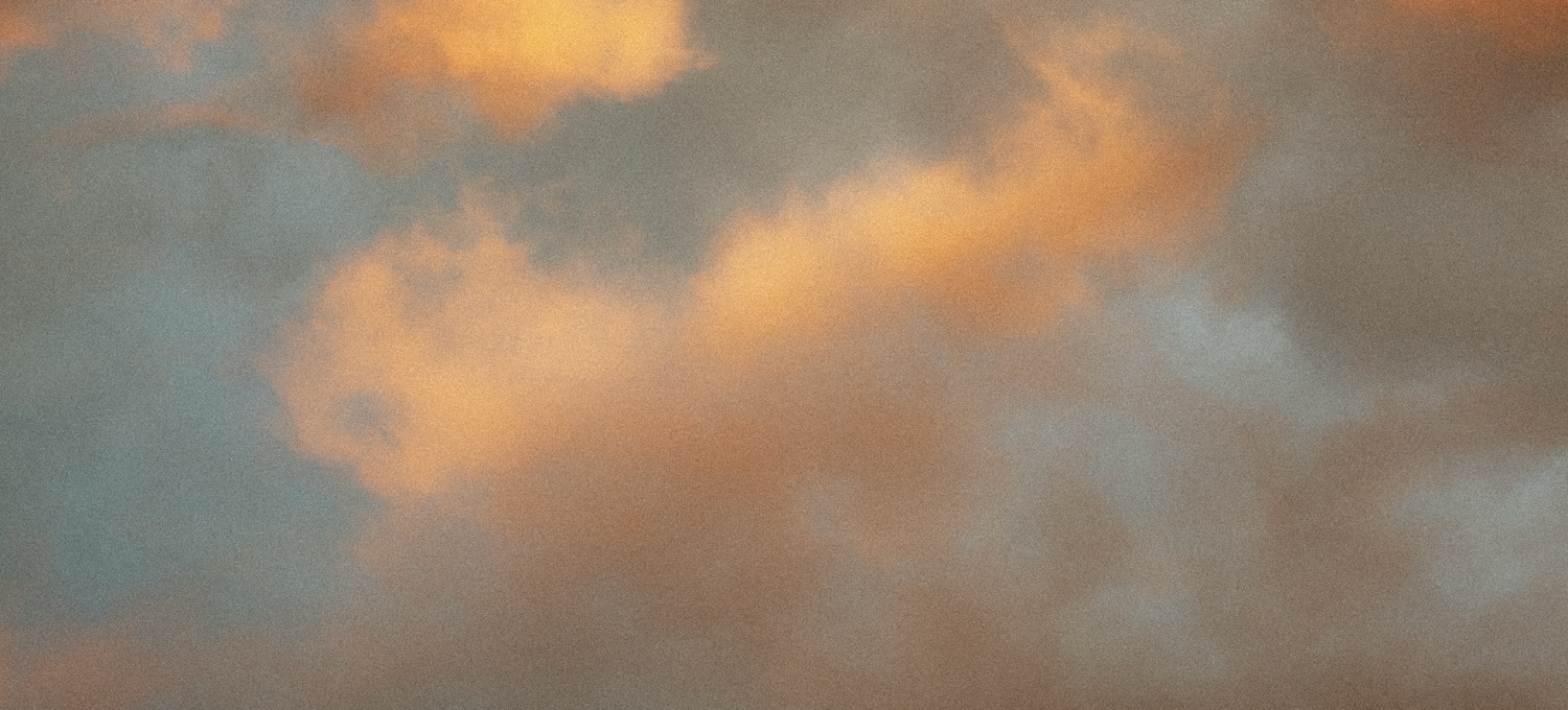 Panoramic view of warm golden sunset clouds against a soft blue-gray sky.