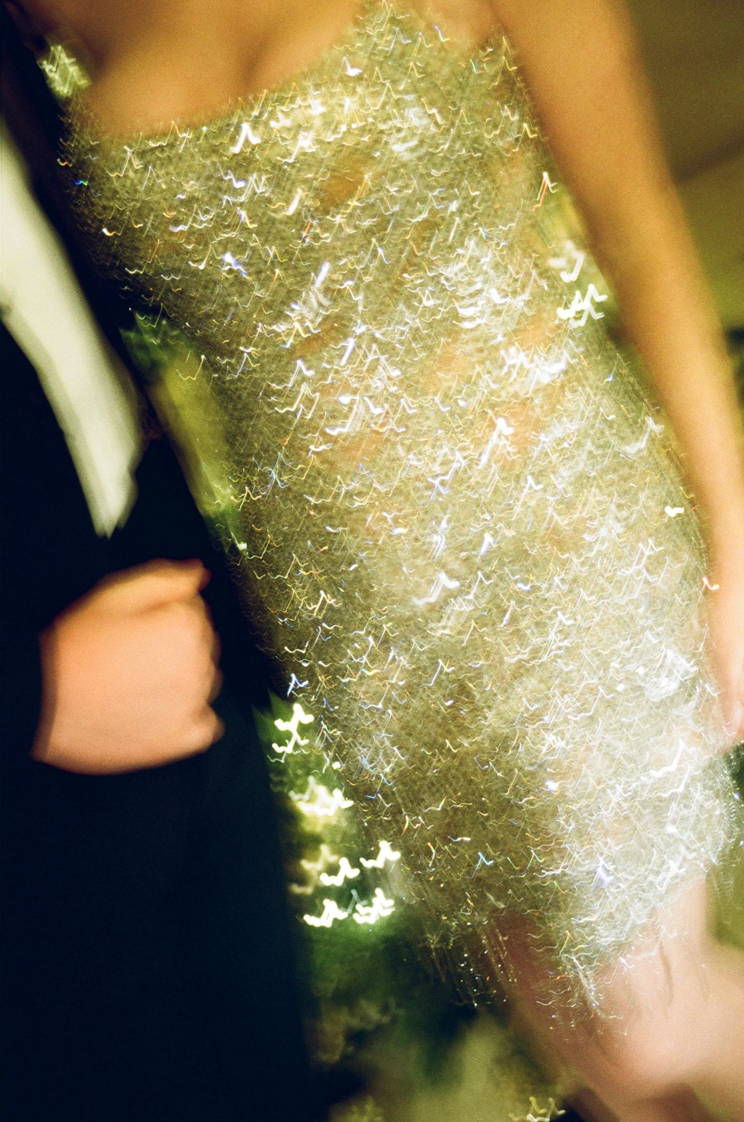 Abstract motion-blurred photograph of a sparkling gold sequined dress at a wedding reception.