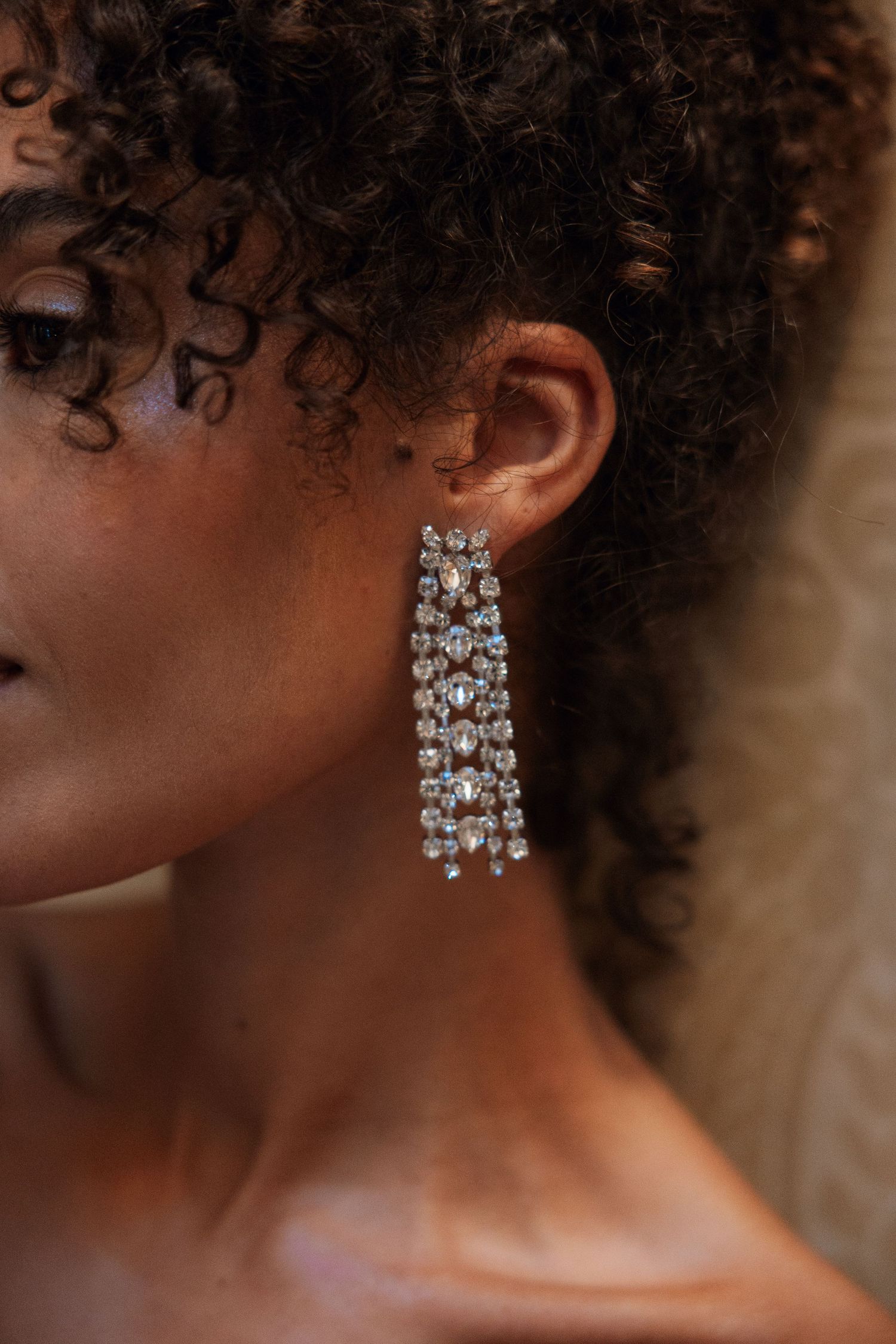 Close-up of a woman wearing sparkling crystal chandelier drop earrings for a wedding.