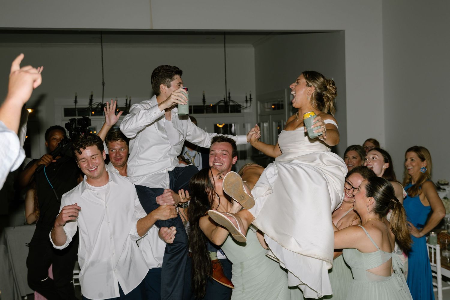 Joyful wedding reception celebration with bride and groom being lifted by guests on the dance floor.
