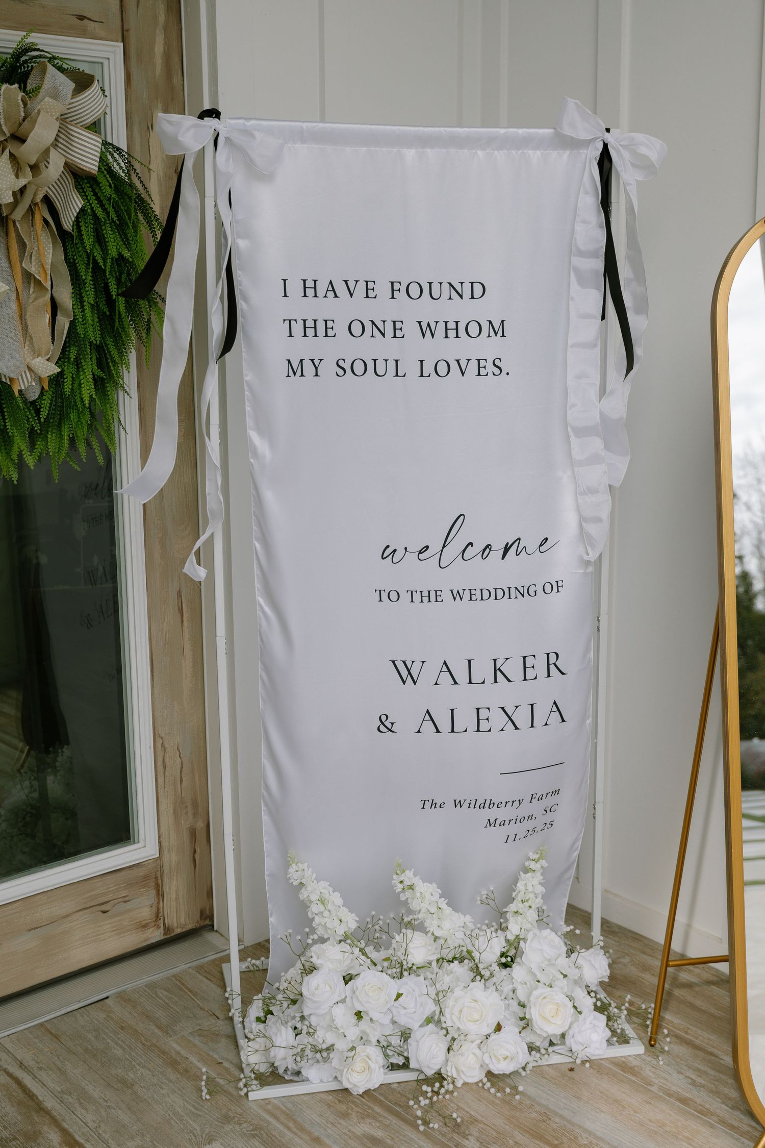 Elegant wedding welcome sign for Walker and Alexia at The Wildberry Farm adorned with white roses.