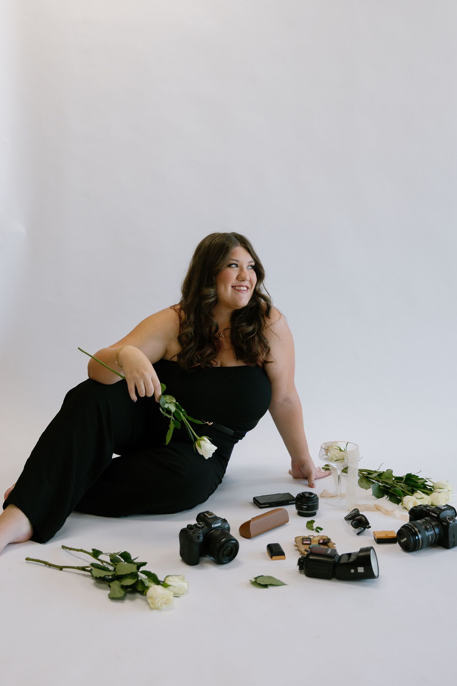 Professional photographer surrounded by cameras and roses during creative portrait session.