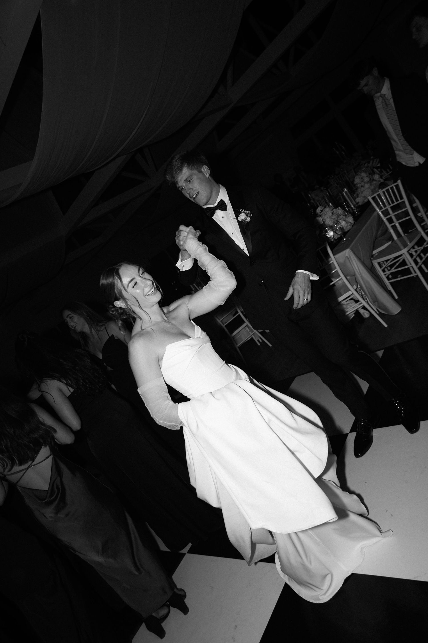Black and white photo of a bride and groom sharing their first dance at an elegant wedding reception.