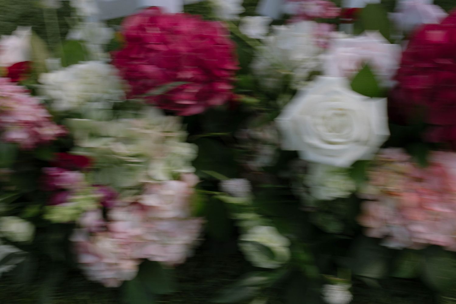 Blurred bouquet of pink hydrangeas, white roses, and magenta flowers creating a soft, dreamy floral arrangement.