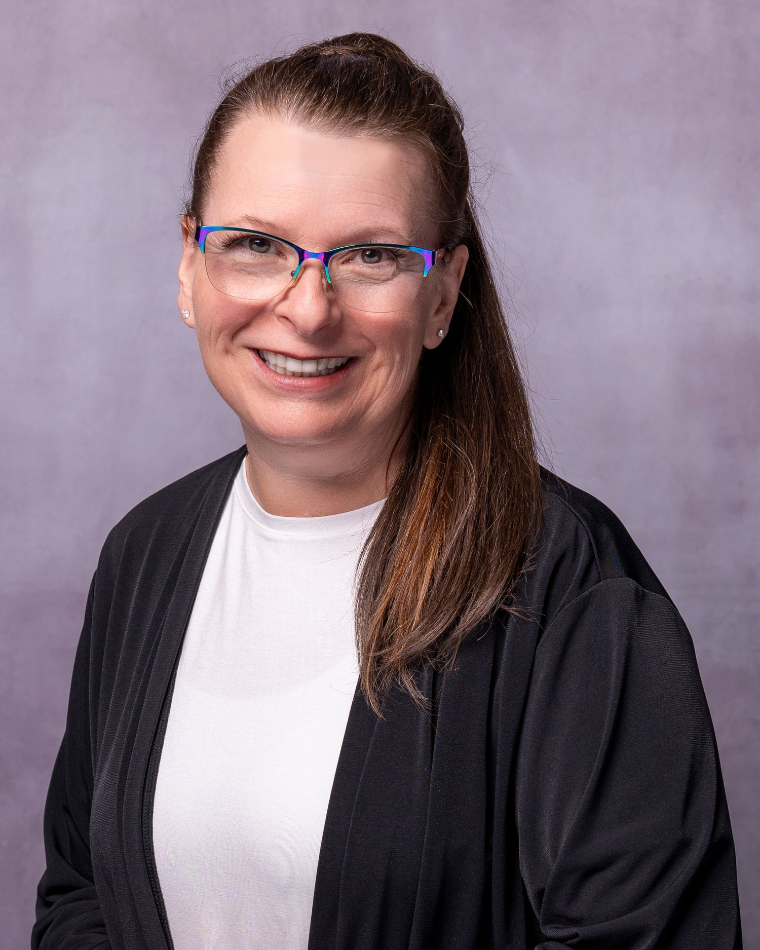 Professional headshot of a smiling woman with glasses and brown hair wearing a black cardigan over a white top.