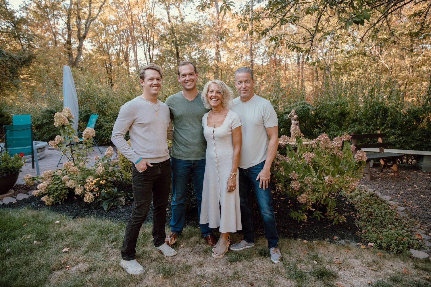 Family of four smiling together in a beautiful autumn garden with colorful foliage.