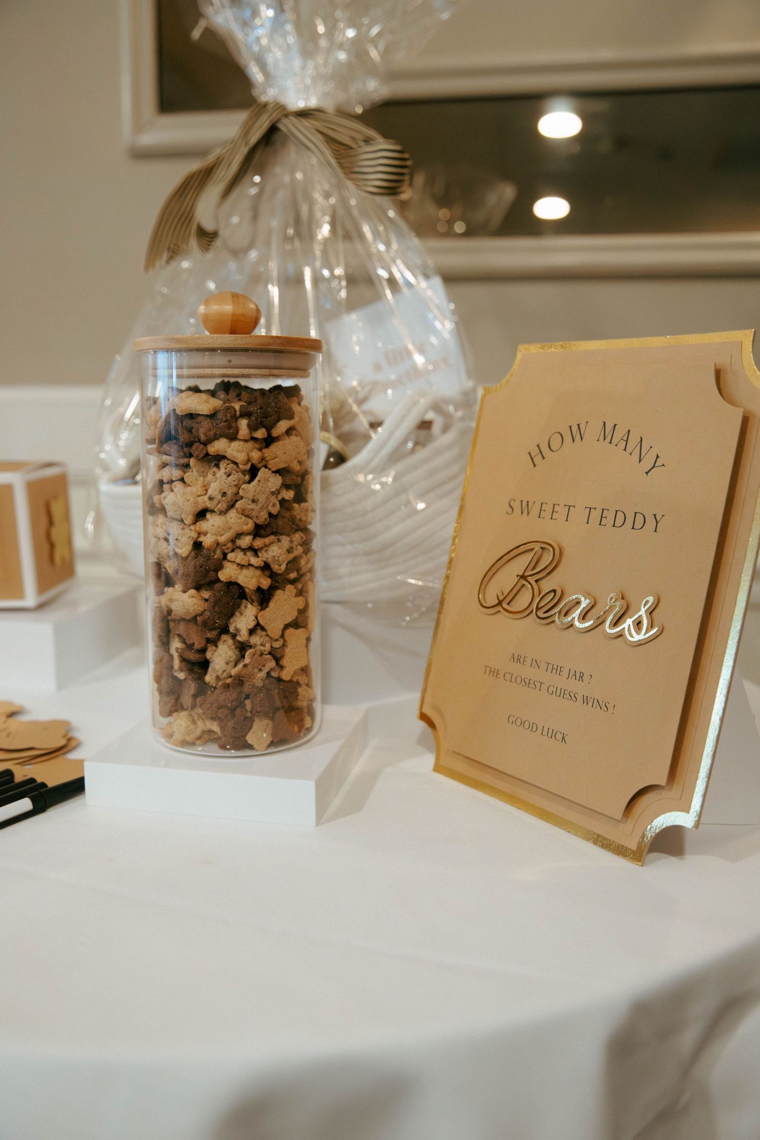 Glass jar filled with teddy bear candies beside gold How Many Sweet Teddy Bears game sign.
