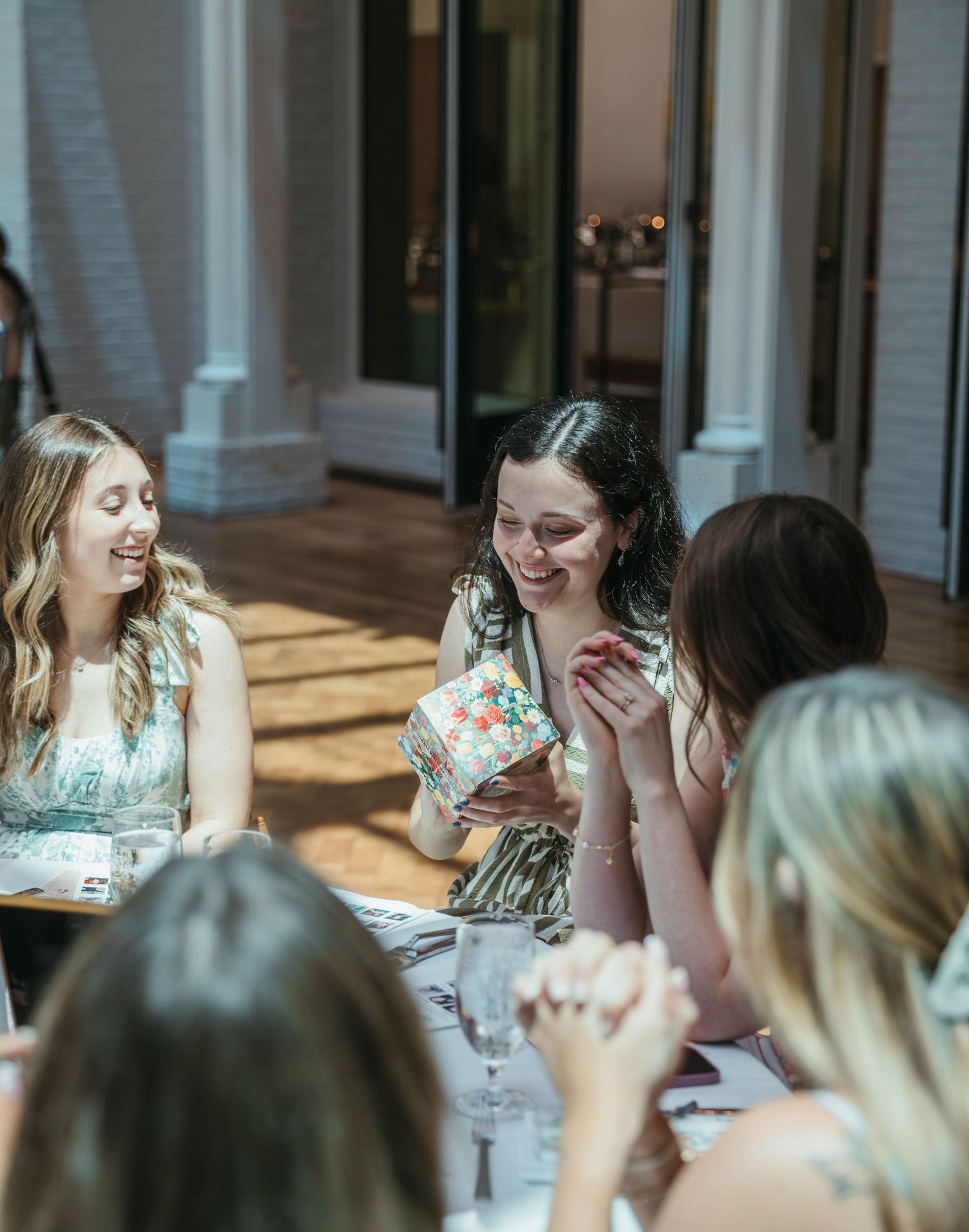 Women laughing and socializing at an elegant indoor dining table during a festive gathering or bridal shower event.
