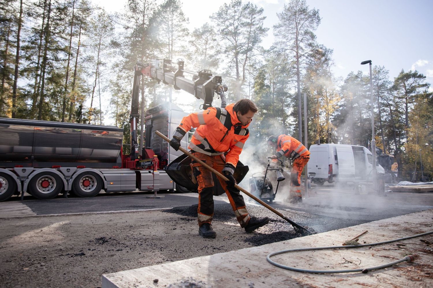 Asfaltsläggning för hand tillsammans med lastbil och kran.