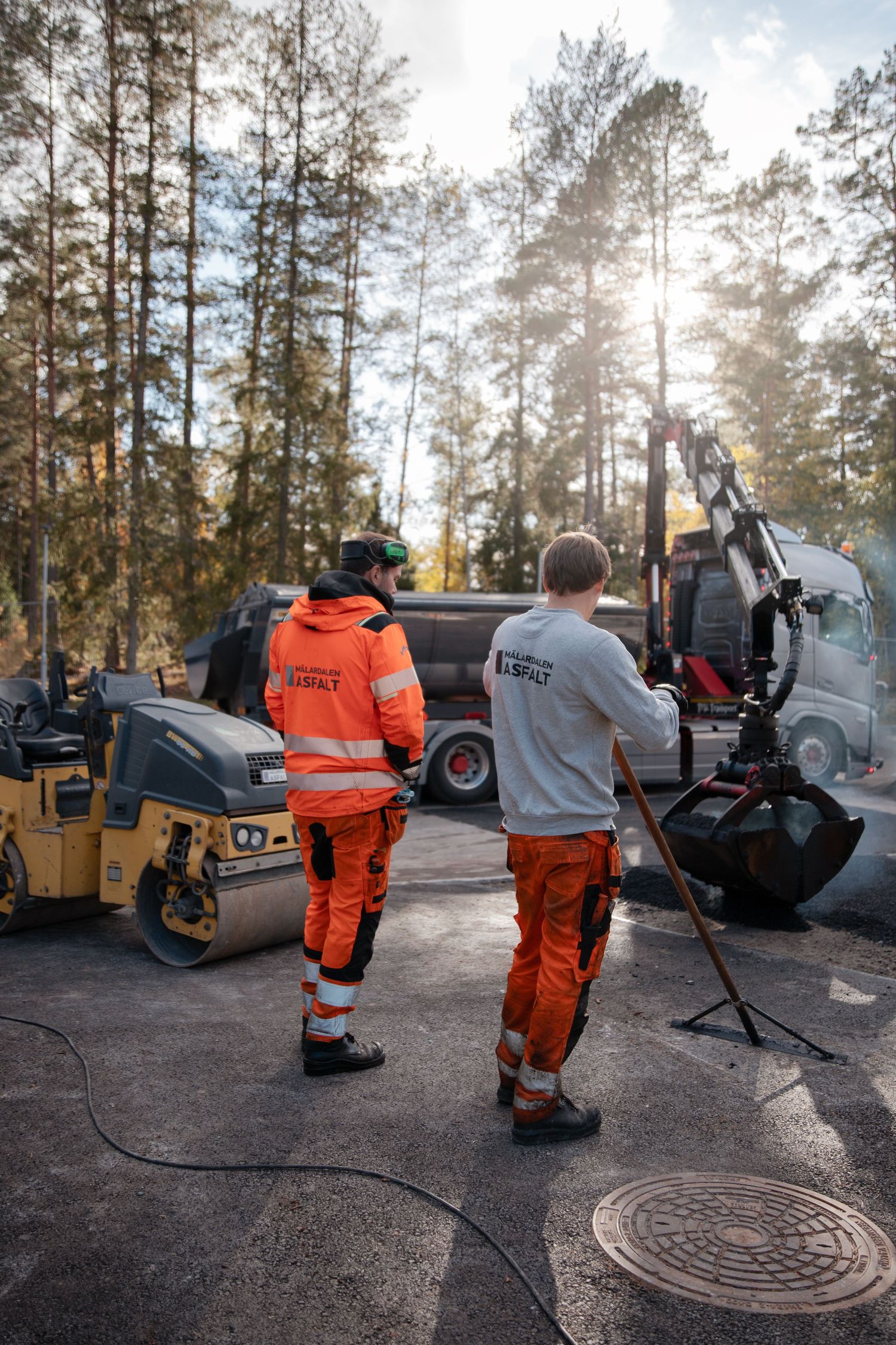Asfaltsläggare väntar på asfalt från lastbilen.
