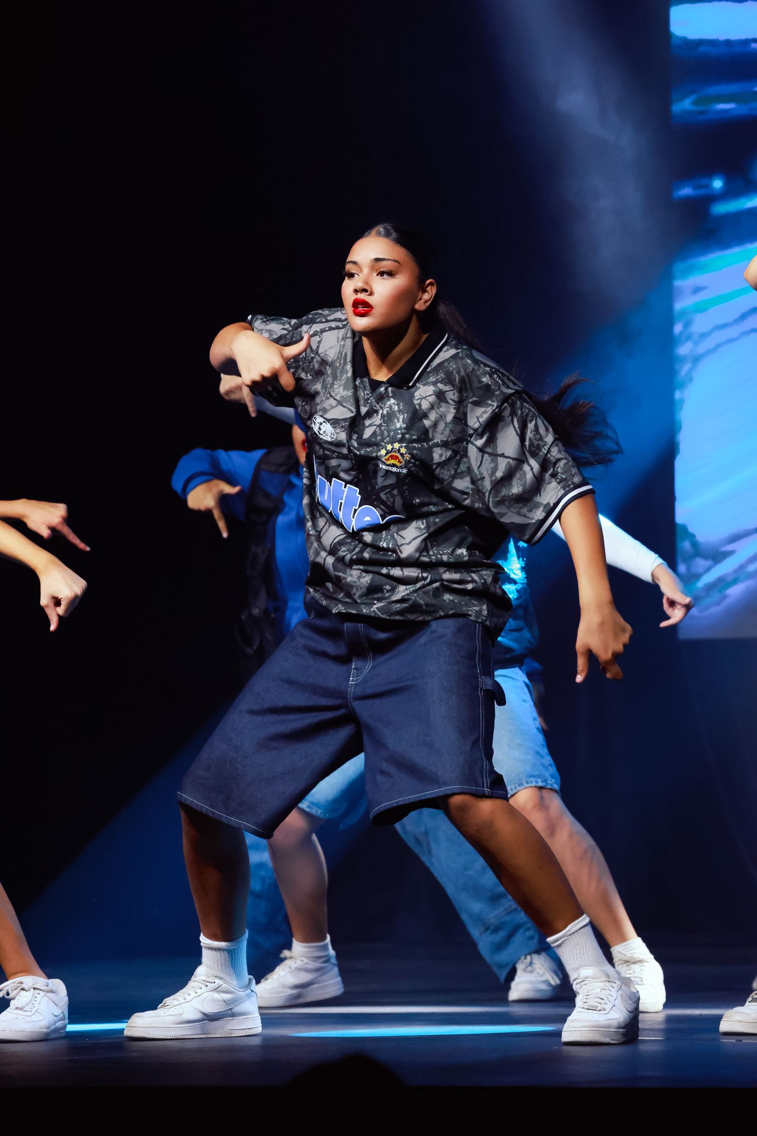 Sydney event photographer and videographer captureStreet dancers in matching outfits perform coordinated moves under dramatic blue lighting.