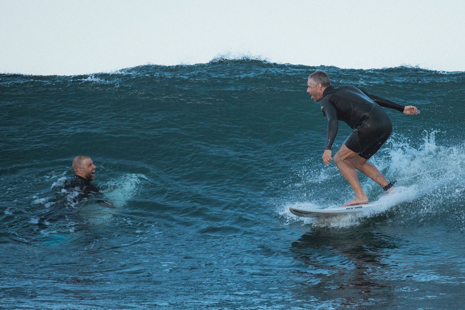 Sutherland Shire photographer captures Two surfers share wave in deep blue ocean water during sunset session.