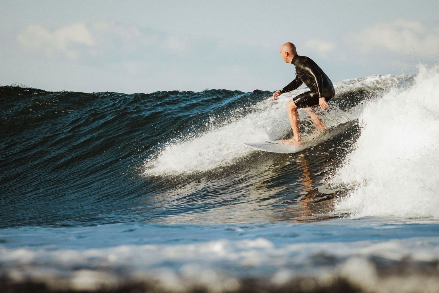 Sydney surf videographer and photographer captures Surfer riding ocean wave at sunset with spray trailing behind at Oak Park Cronulla Sydney