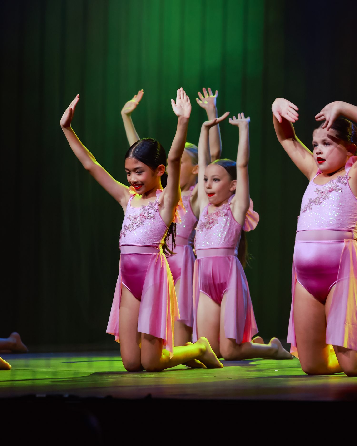 Wollongong dance and concert photographer Dance ensemble in pink costumes performs floor choreography on green-lit stage.
