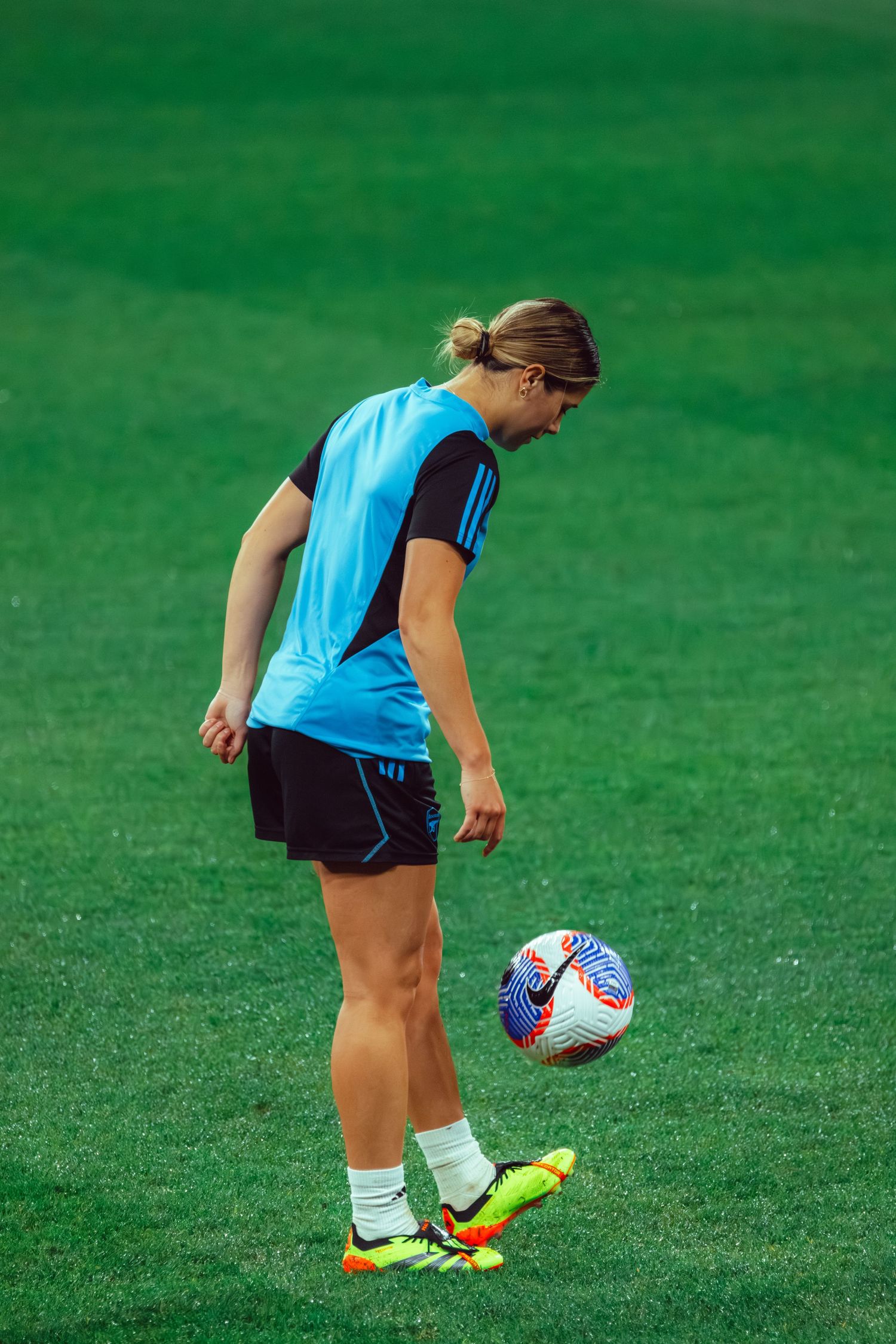Sydney sports photographer captures Soccer player in light blue uniform practices ball control drills on grass field.