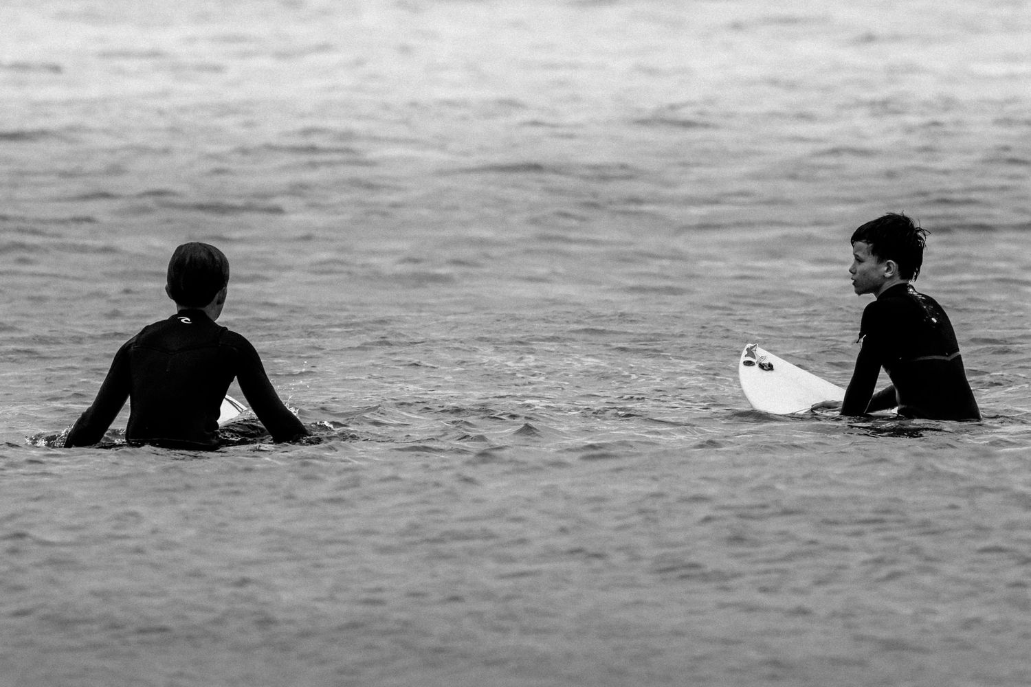 Sydney Sutherland Shire photographer and videographer Silhouettes of surfers sitting on their boards in calm waters waiting for waves.
