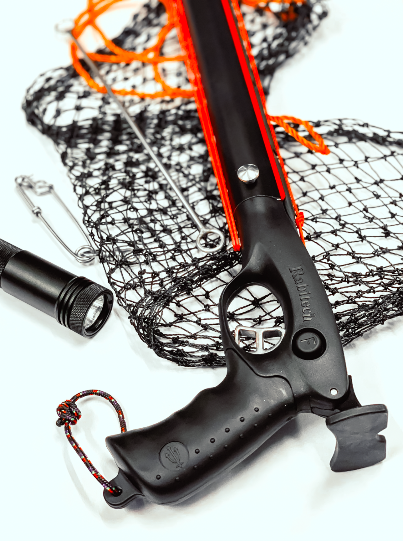 Close-up professional product photograph red and orange speargun mechanism with mesh netting displayed on white background.