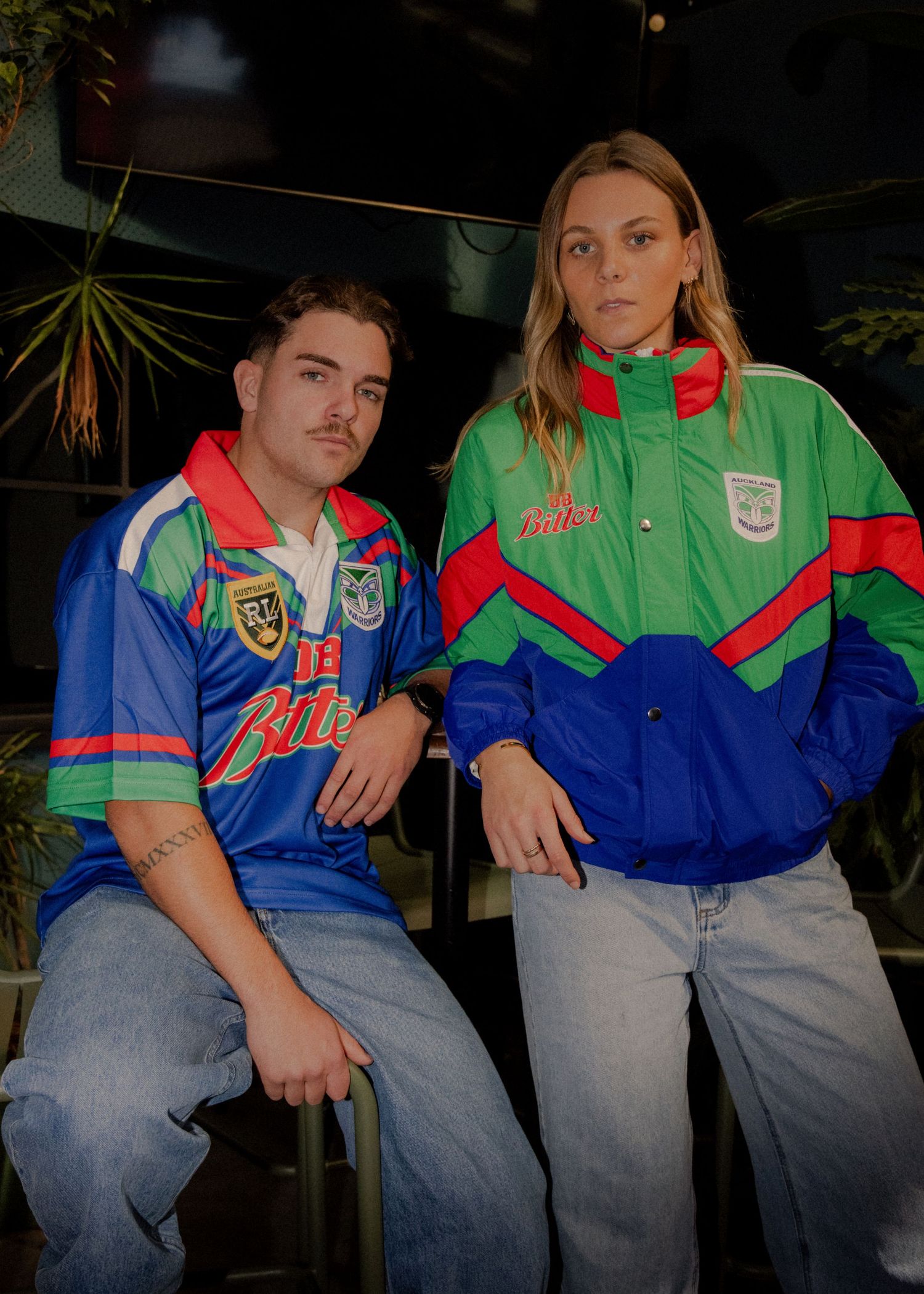 Two models wearing retro Canberra Raiders NRL jersey and green jacket pose together in a casual outdoor setting. Wollongong photography