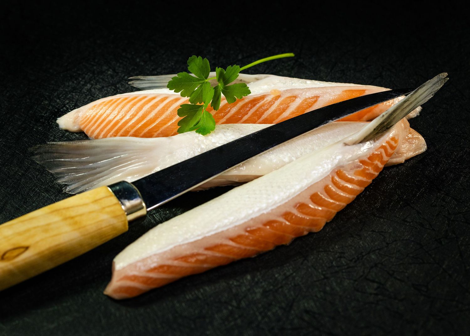 Food and product photography and videography Fresh salmon fillets with herbs arranged on dark slate background.