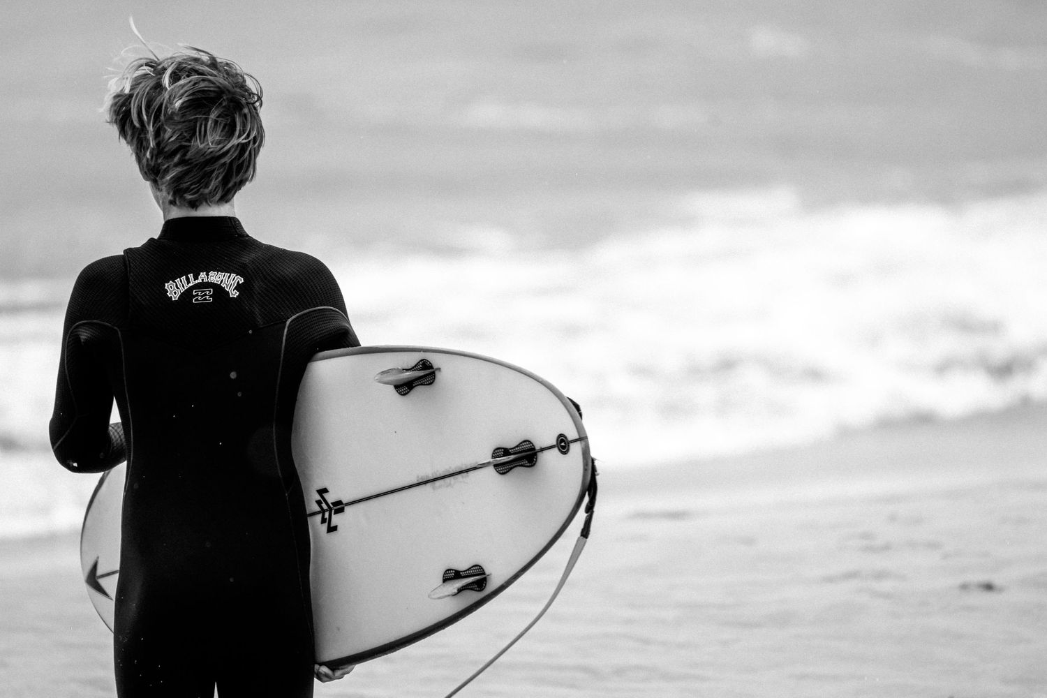 Sydney Sutherland Shire photographer and videographer Black and white panoramic view of surfers walking along the shoreline with boards.