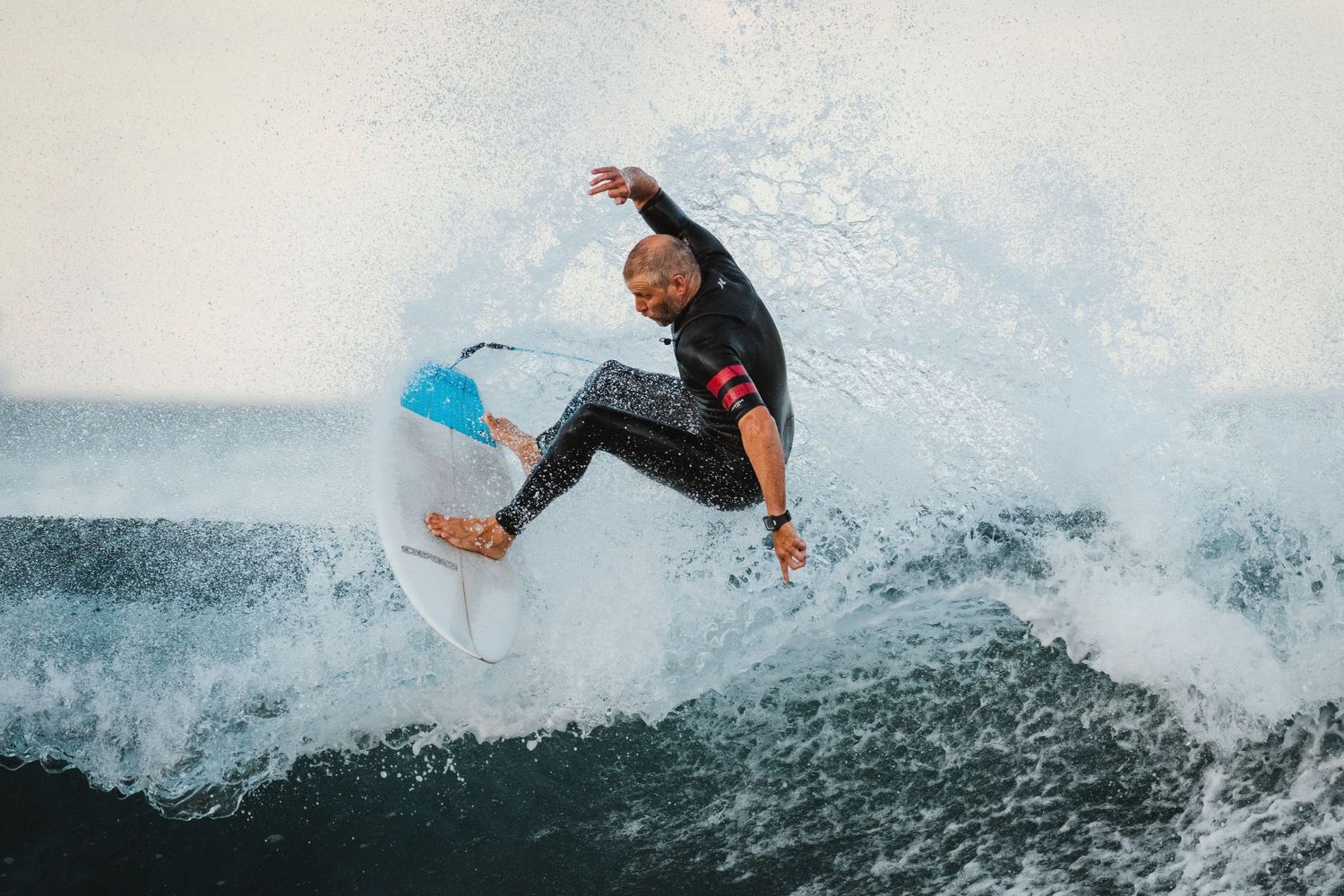 Wollongong photographer and videographer Surfer riding through ocean waves while performing high-energy maneuvers in wetsuit.