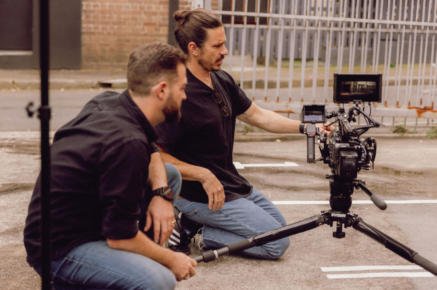 Camera operators setting up low-angle shots on concrete surface. Professional videographer in sydney