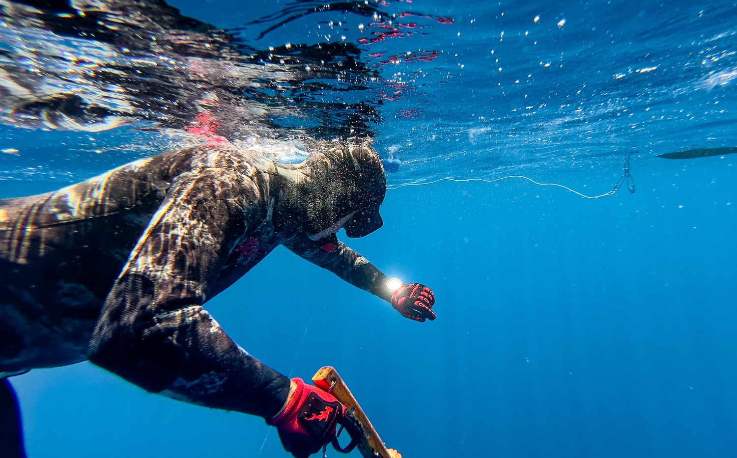 Underwater videography and photography film still of diver swimming in clear blue ocean water spearfishing