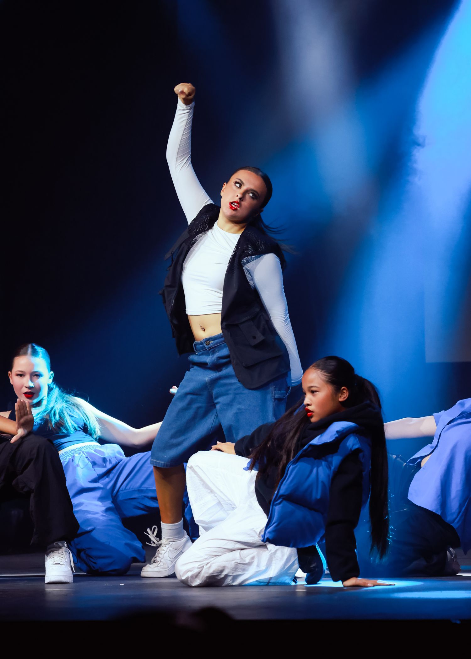 Sydney concert photographer Contemporary dancers in blue and white costumes perform floor choreography under spotlights.