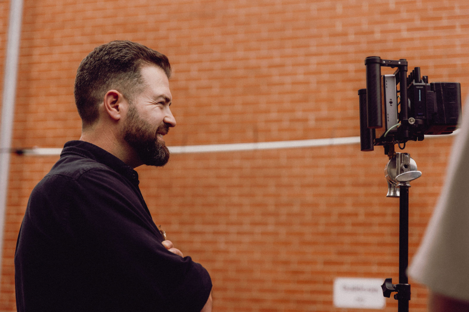 Videographer positions camera equipment outdoors near brick building. Professional videographer in sydney