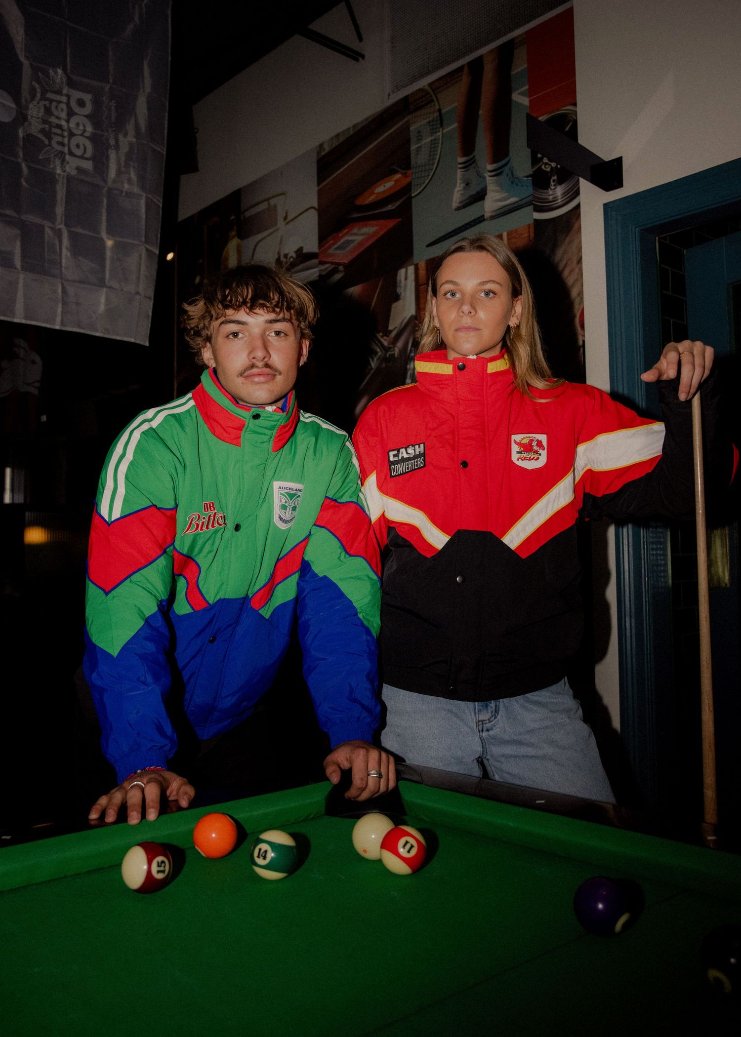 Two models in retro colorful sports jackets pose at a pool table in a bar setting. Sutherland Shire photographer