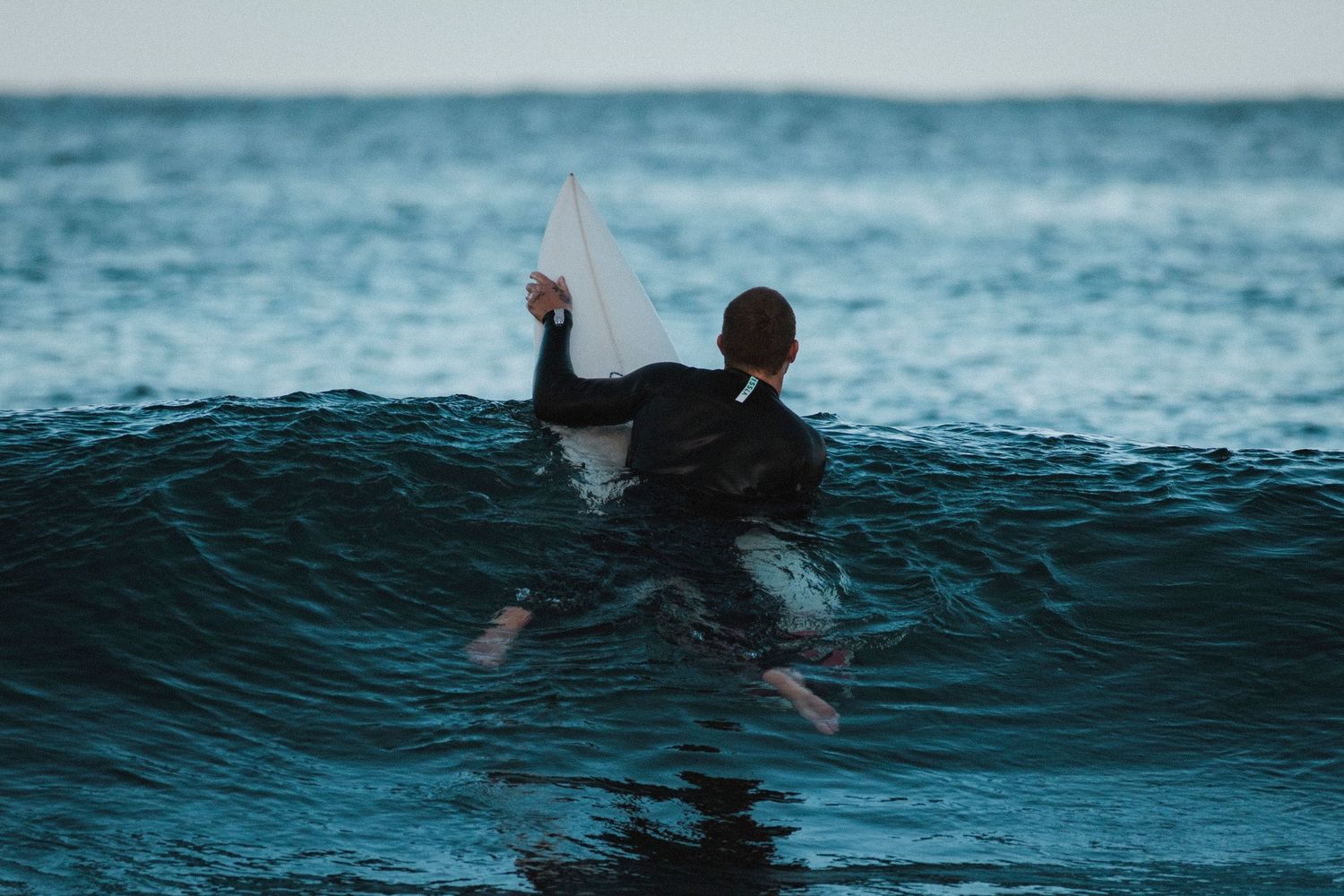 Sutherland Shire photographer captures Silhouetted surfer checks wave while paddling out at dusk.