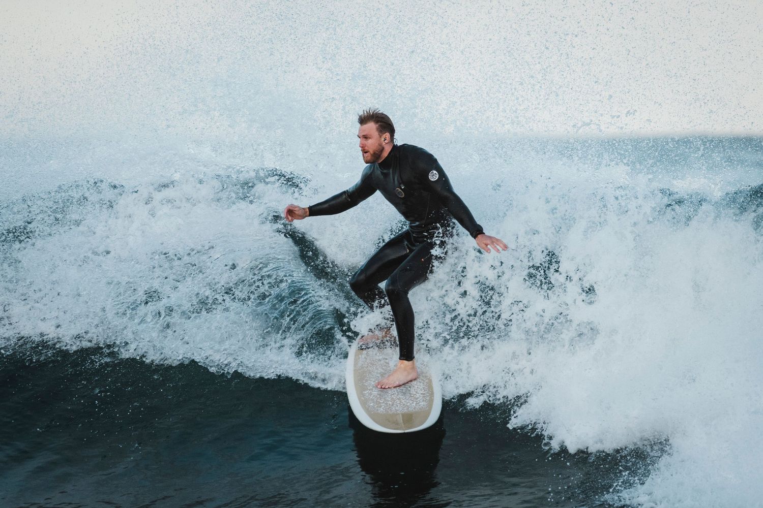 Wollongong Shire photographer captures Surfer stands tall on surfboard while riding through powerful ocean wave.