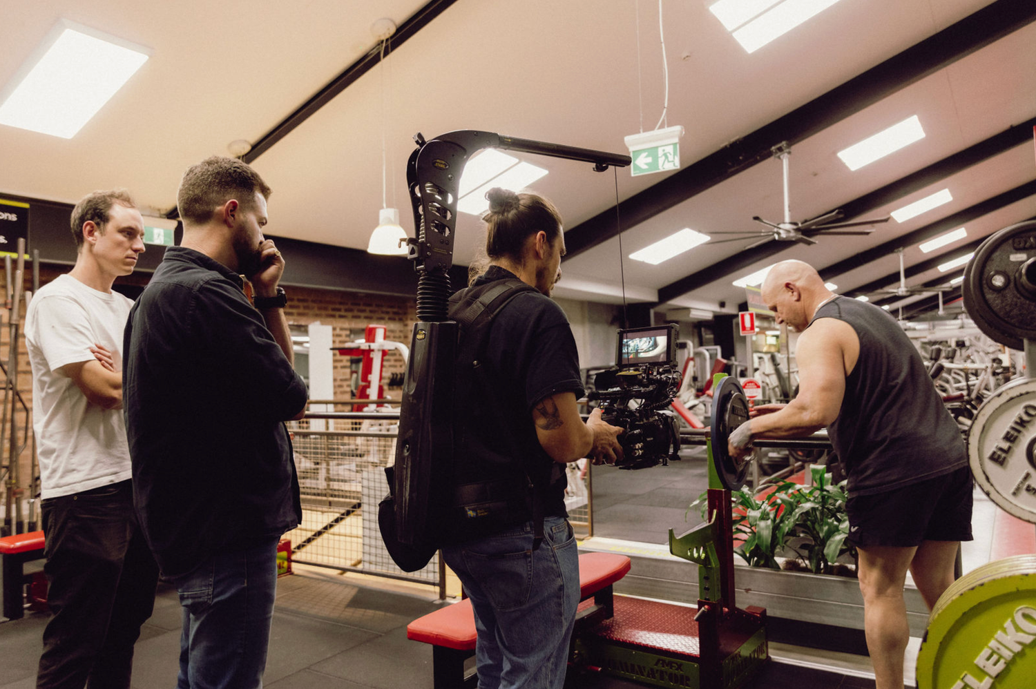 Production team collaborating in industrial workspace with professional camera gear. Professional videographer in sydney
