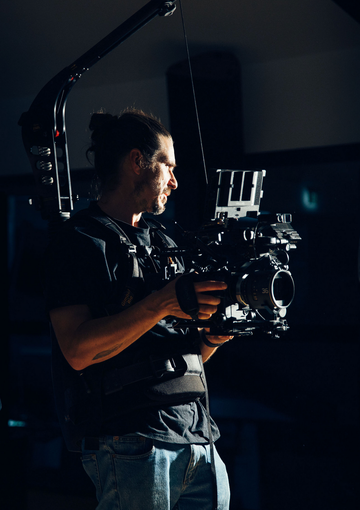 Silhouetted camera operator using professional filming equipment in a dark studio environment. Professional videographer in sydney