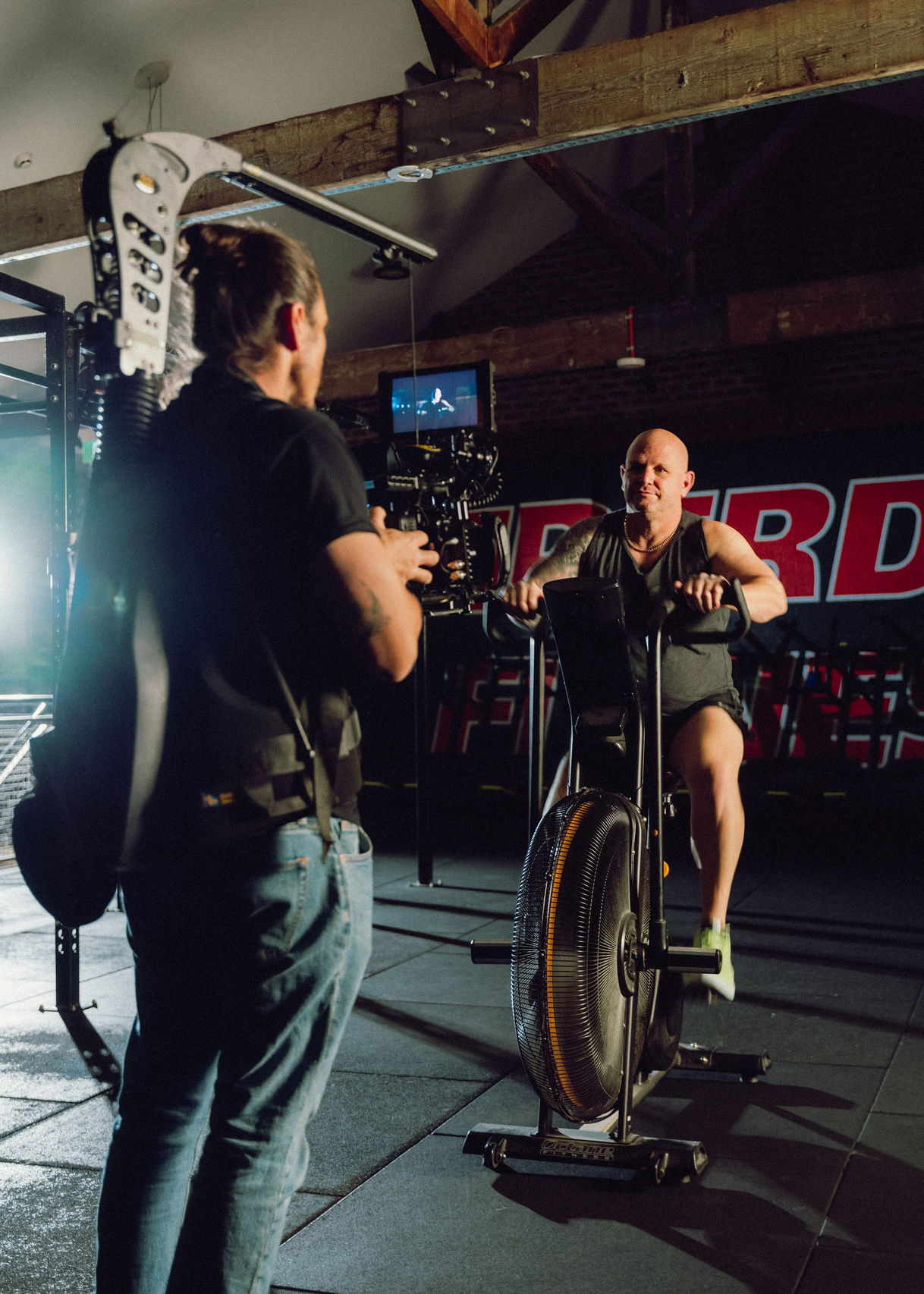 Camera operator filming in a dimly lit gym or fitness facility. Professional videographer in sydney