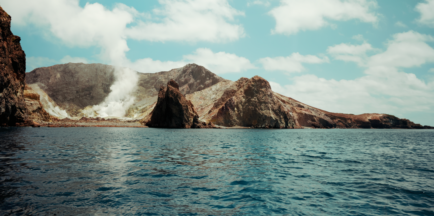 Sydney Sutherland Shire professional photo and video Rocky coastal landscape with steam rising from volcanic formations over blue waters.