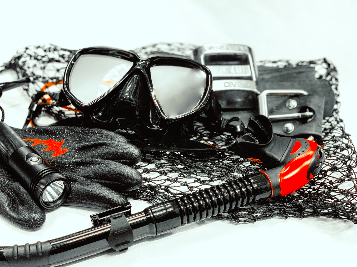Close-up professional product photograph Diving equipment including mask and snorkel laid out on black mesh netting.
