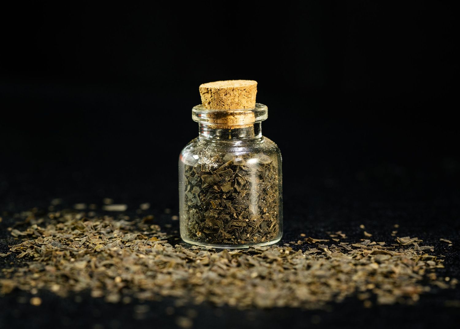 Food and product photography and videography Small glass jars filled with golden spices against dark background.