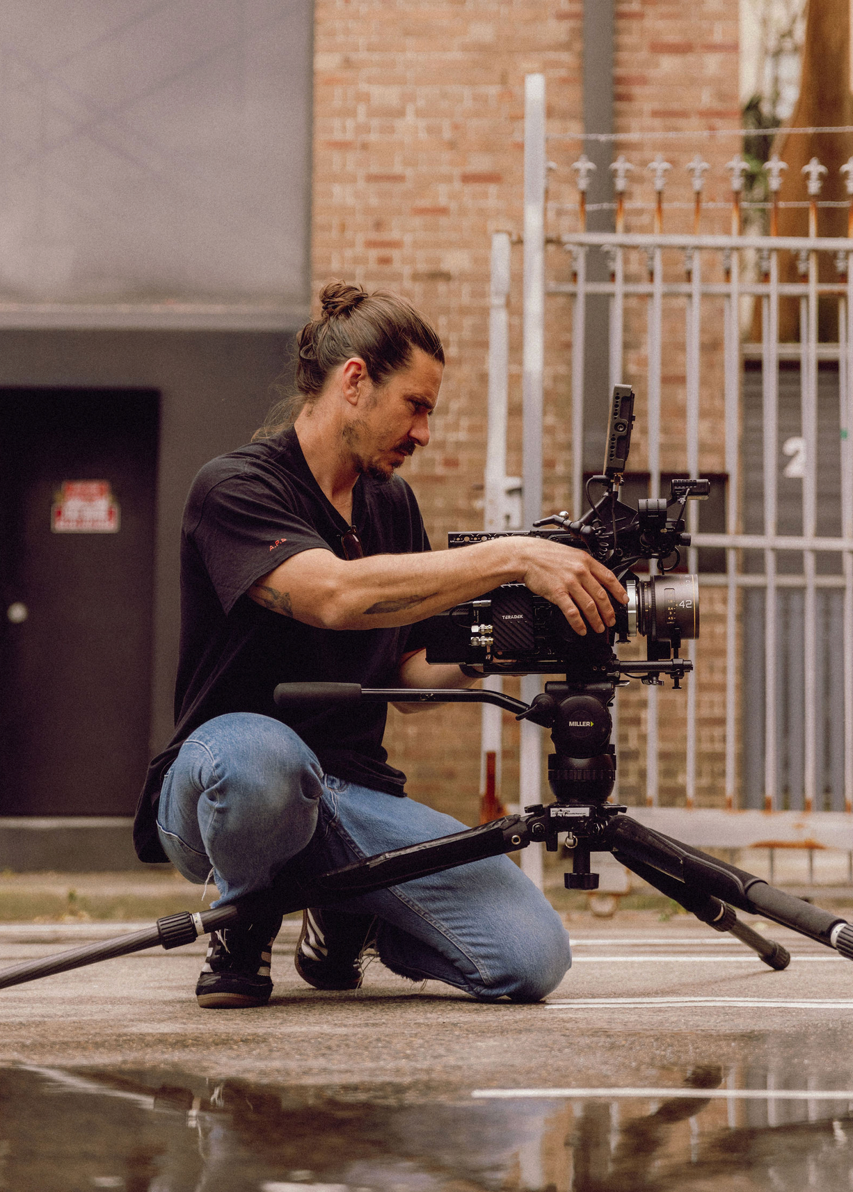 Camera operator capturing low-angle shots on wet concrete surface. Professional videographer in sydney